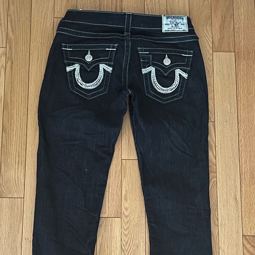 Dark blue low rise size 26 true religion jeans with white stitching.